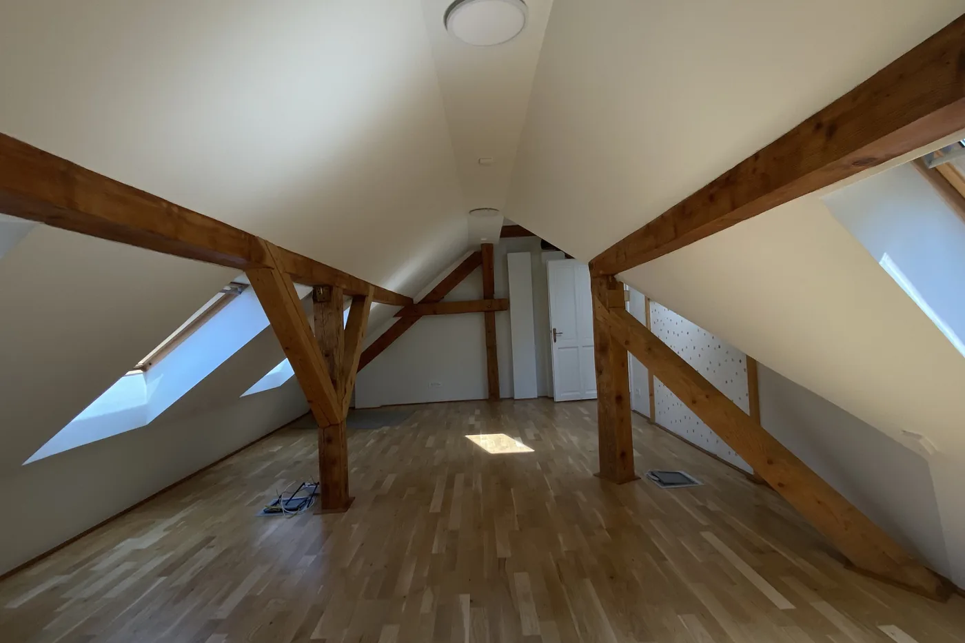O cameră goală din apartamentul 9, cu soarele de la ferestrele de acoperiș pe parchet